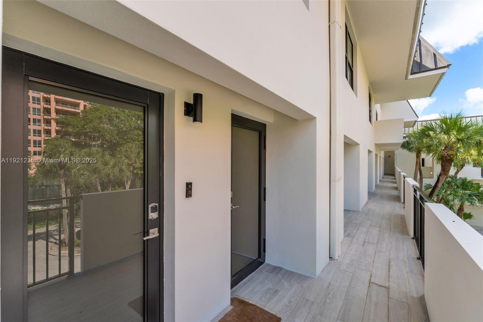 An outdoor balcony features light-colored wood-look tile flooring and two dark-framed glass doors — 6901 Edgewater Dr # 315, Coral Gables FL 33133, CORAL GABLES, FL