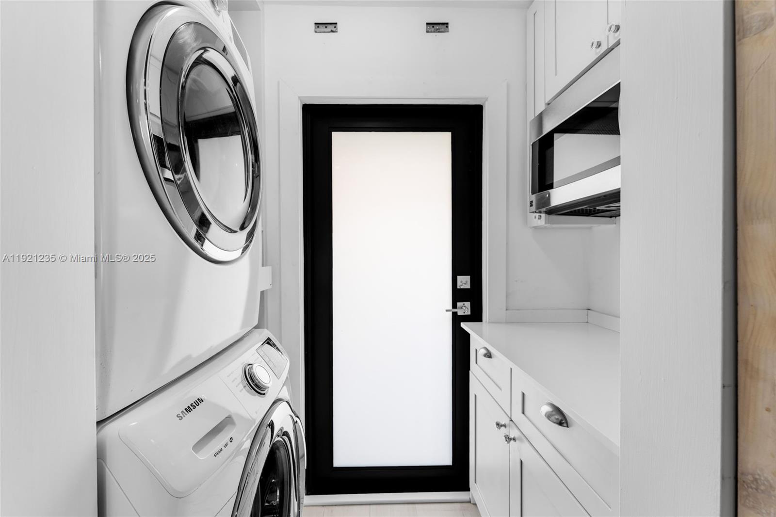 A laundry room features a stacked Samsung washer and dryer, white cabinetry, and a door — 6901 Edgewater Dr # 315, Coral Gables FL 33133, CORAL GABLES, FL