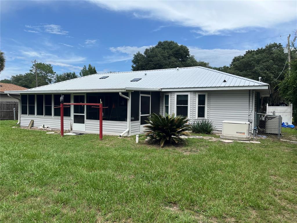 A single-story house with a metal roof, screened-in porch, and a Generac generator outside — 2392 SE 175TH TERRACE ROAD, SILVER SPRINGS, FL