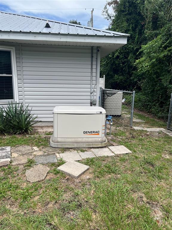 A Generac standby generator sits on a concrete pad next to a light-sided house — 2392 SE 175TH TERRACE ROAD, SILVER SPRINGS, FL