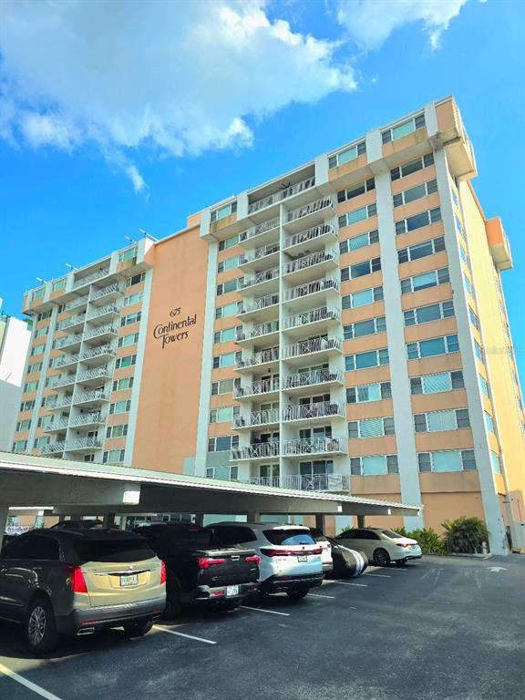 A multi-story apartment building with balconies and a covered parking area in the foreground — 675 S GULFVIEW BOULEVARD UNIT 505, CLEARWATER BEACH, FL