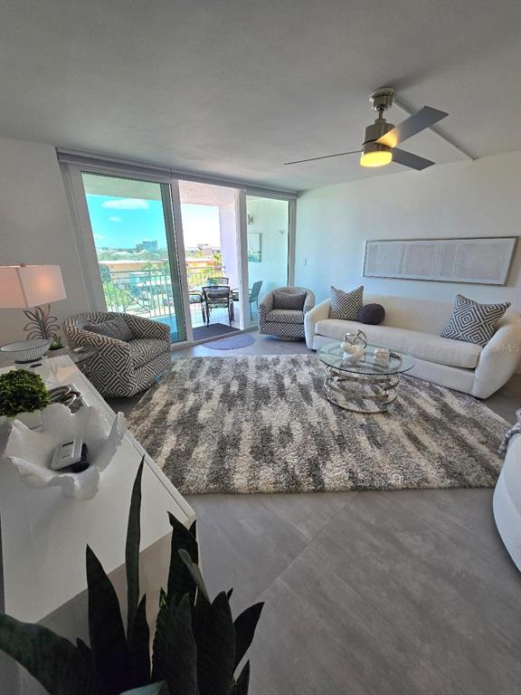 A modern living room features a white sofa, patterned armchairs, a shaggy rug, and balcony access — 675 S GULFVIEW BOULEVARD UNIT 505, CLEARWATER BEACH, FL