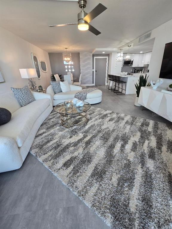 A living room features a white sofa, a patterned rug, and an open-concept kitchen — 675 S GULFVIEW BOULEVARD UNIT 505, CLEARWATER BEACH, FL