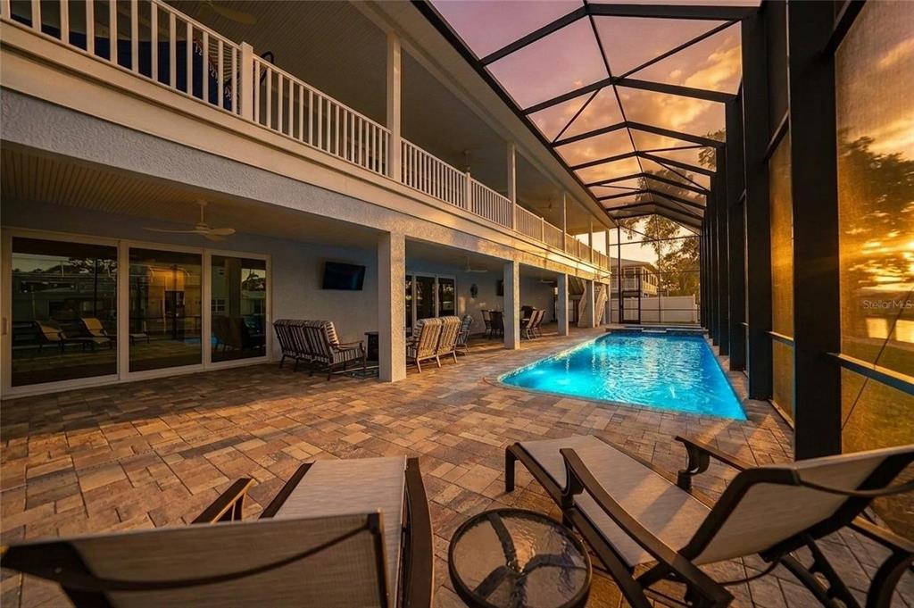 A covered patio features a swimming pool, outdoor furniture, and a two-story balcony structure — 9240 PINE COVE DRIVE, ENGLEWOOD, FL