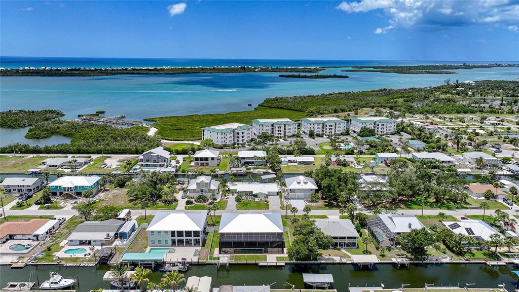 An aerial view shows waterfront houses with boat docks along a canal near the ocean — 9240 PINE COVE DRIVE, ENGLEWOOD, FL
