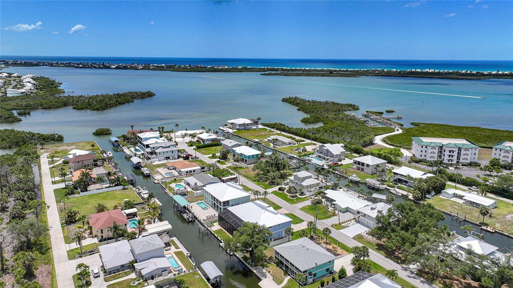 An aerial view shows waterfront houses with private docks along a canal near the ocean — 9240 PINE COVE DRIVE, ENGLEWOOD, FL