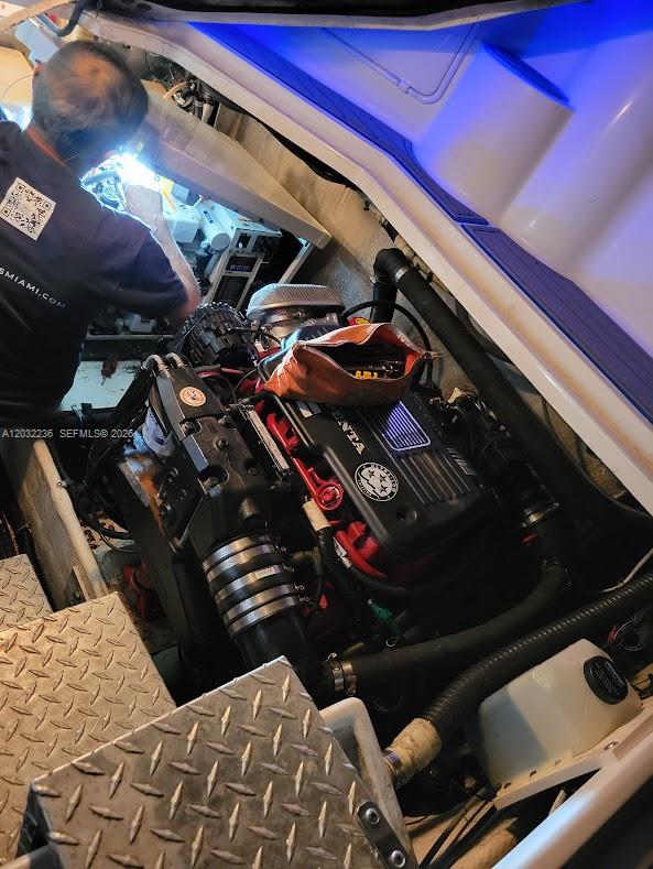 A mechanic works on a boat engine inside an engine compartment with diamond-plate flooring — 1700 NW 97 AVE, SUITE 227641, Miami FL 33172, MIAMI, FL