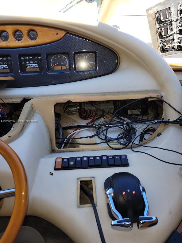 A boat helm station features exposed wiring, Caterpillar gauges, a steering wheel, and throttle controls — 1700 NW 97 AVE, SUITE 227641, Miami FL 33172, MIAMI, FL