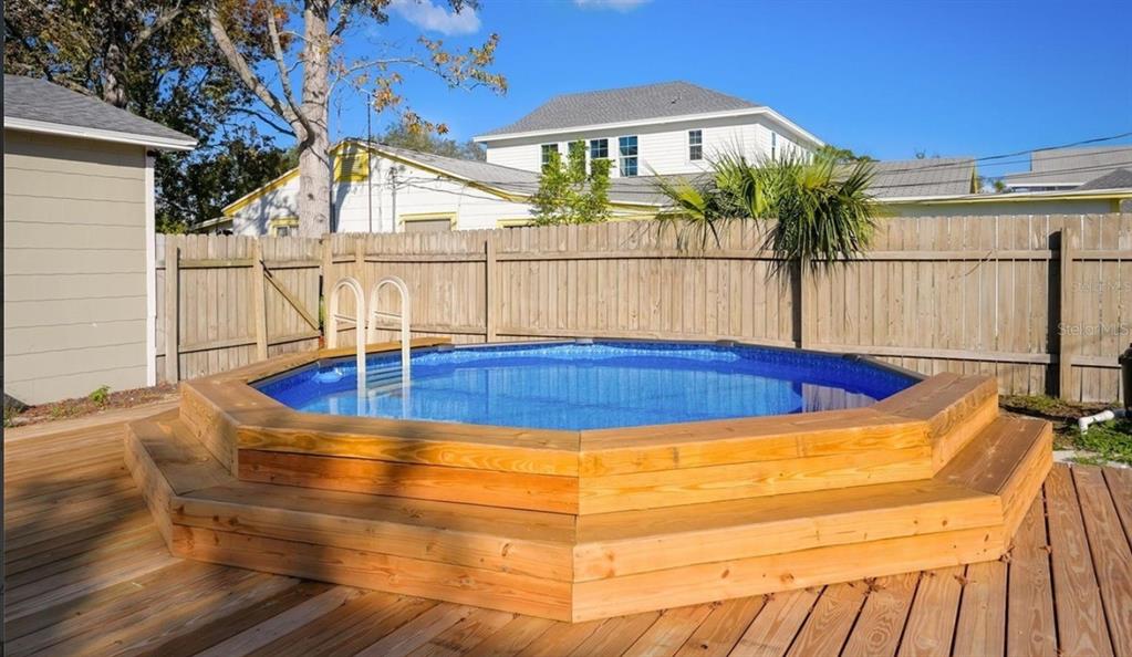 An octagonal above-ground pool with a wooden deck and stairs sits in a fenced backyard — 5340 5TH AVENUE S, ST PETERSBURG, FL