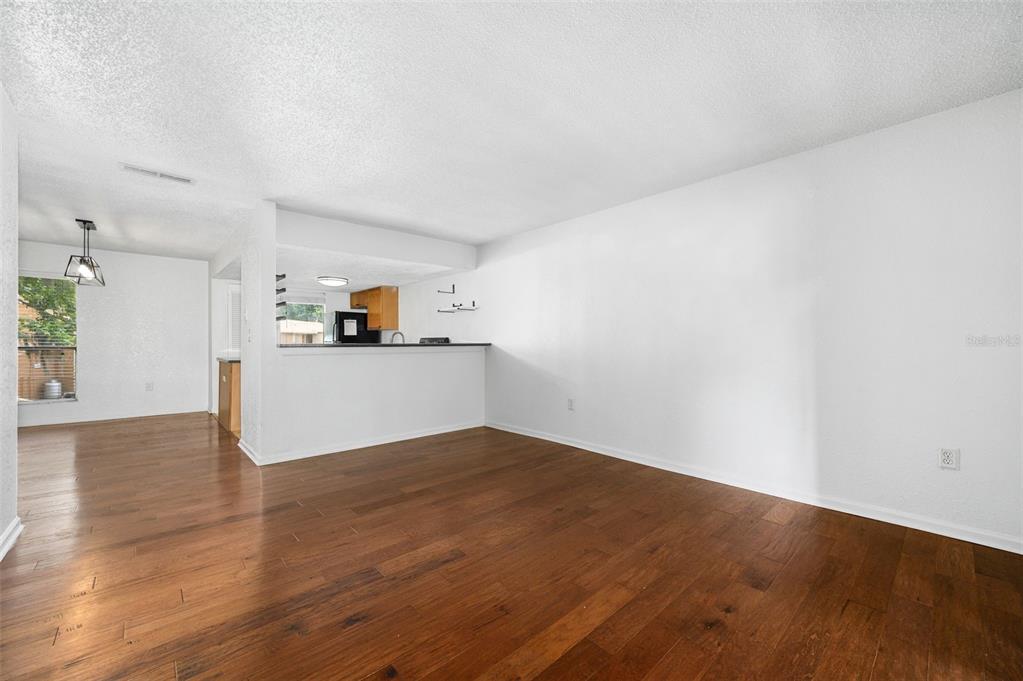 An open living area features hardwood floors, white walls, and a pass-through kitchen counter — 1810 NW 23RD BOULEVARD UNIT 151, GAINESVILLE, FL