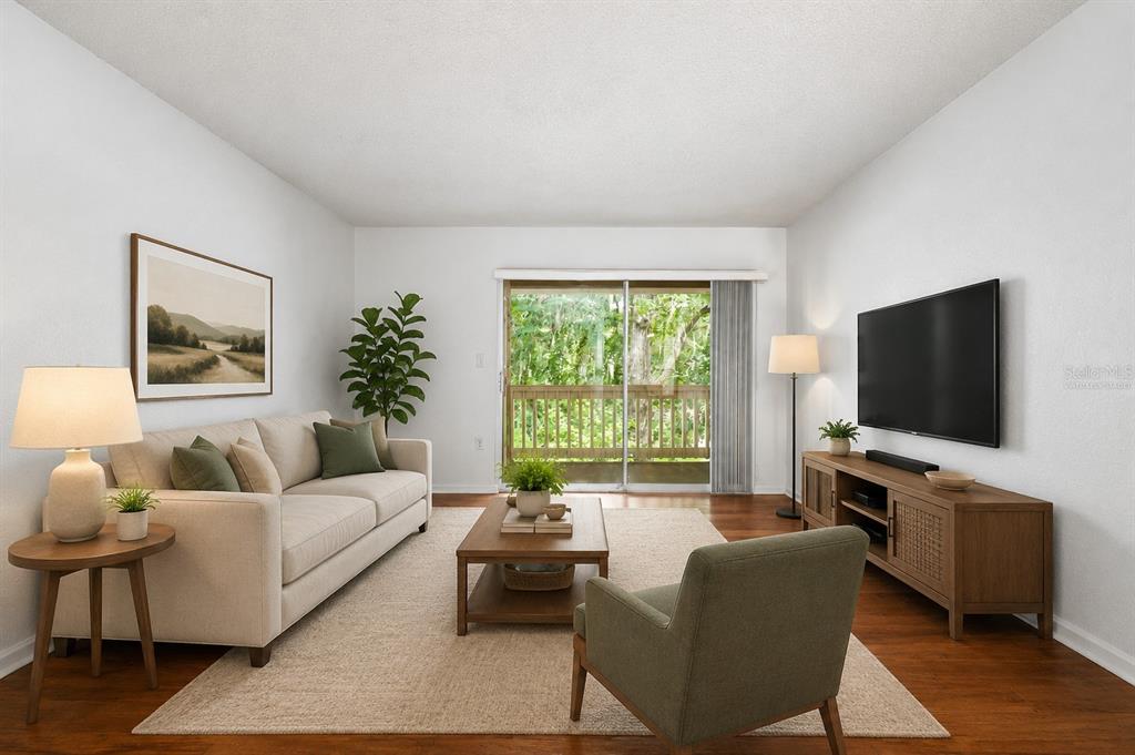 A living room with a beige sofa, wooden coffee table, television, and sliding glass balcony doors — 1810 NW 23RD BOULEVARD UNIT 151, GAINESVILLE, FL