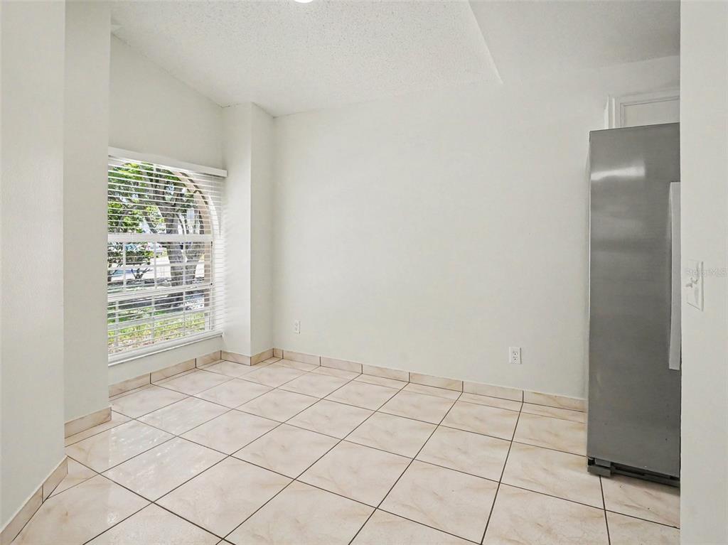 A bright room with white walls, tiled floors, a large arched window, and a refrigerator — 9910 N DEAN OAKS COURT, ORLANDO, FL