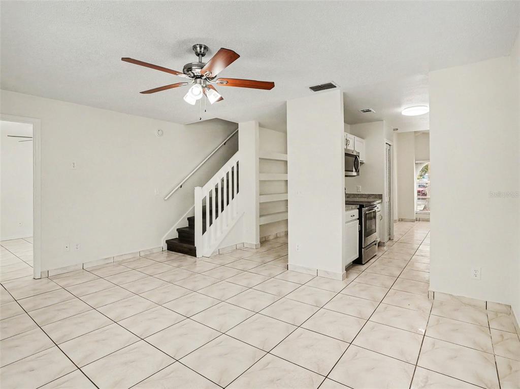 A tiled living area features a staircase, built-in shelving, and an adjacent kitchen — 9910 N DEAN OAKS COURT, ORLANDO, FL
