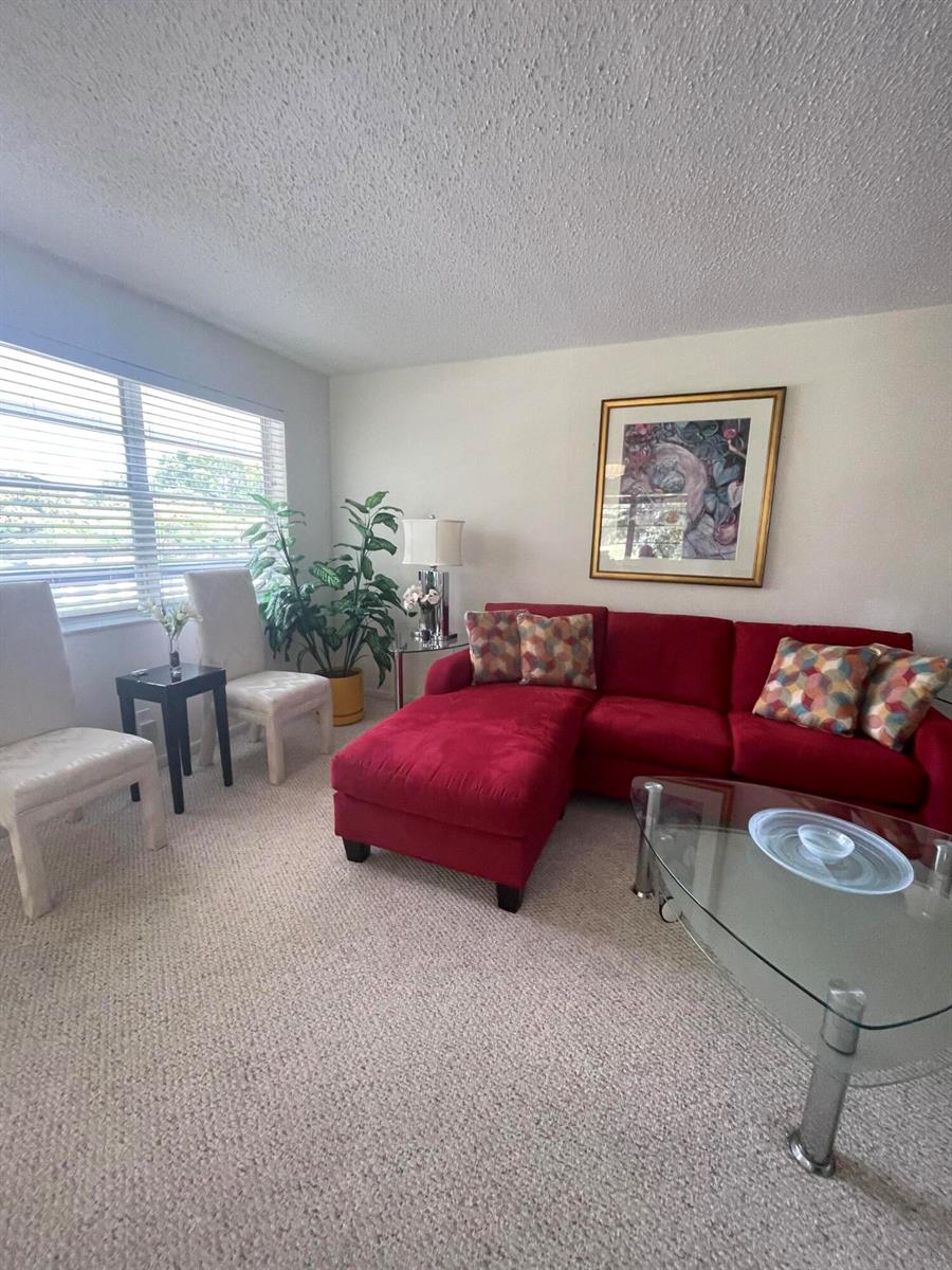 A living room features a red sectional sofa, a glass coffee table, and two chairs — 40 Keswick # 40, Deerfield Beach FL 33442, DEERFIELD BEACH, FL