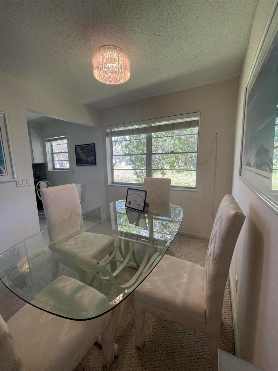 A dining room features a glass-topped table, four upholstered chairs, and a crystal light fixture — 40 Keswick # 40, Deerfield Beach FL 33442, DEERFIELD BEACH, FL