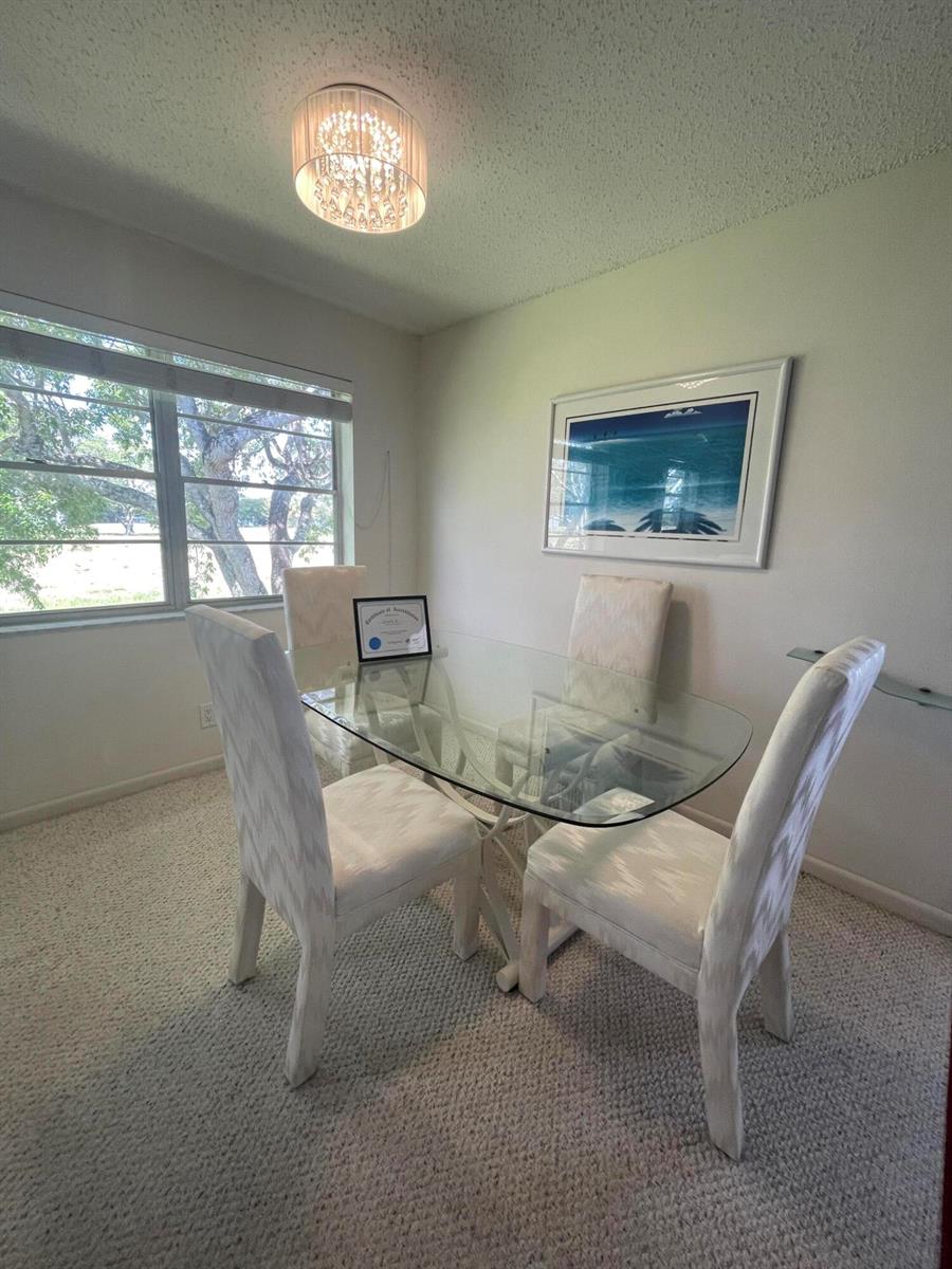 A dining room features a glass-topped table, four upholstered chairs, and a crystal light fixture — 40 Keswick # 40, Deerfield Beach FL 33442, DEERFIELD BEACH, FL