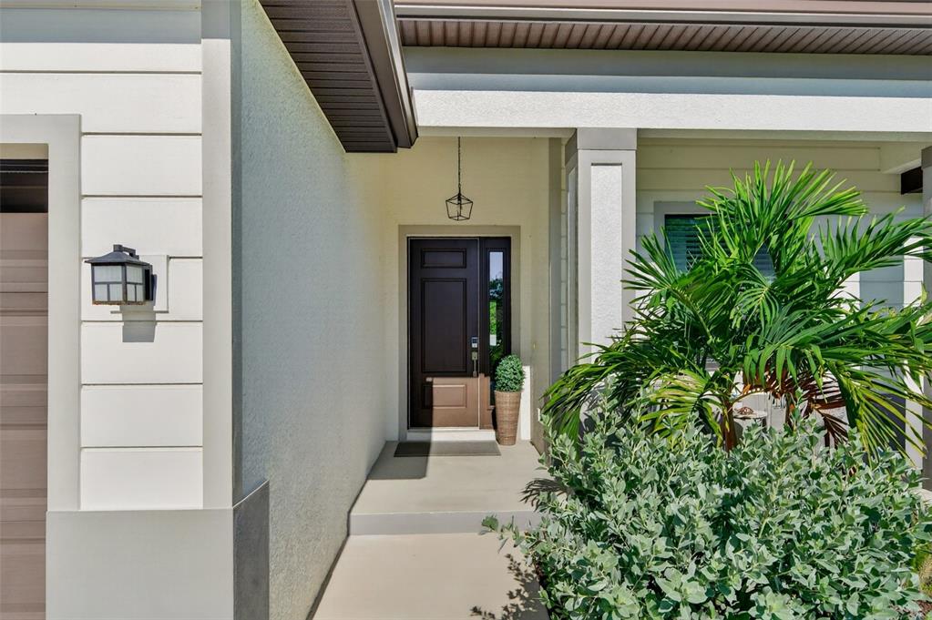 A covered entryway features a dark brown front door, a hanging lantern, and a small palm — 5178 FLORIDA ROAD, VENICE, FL