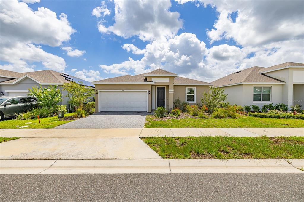 A single-story suburban house with a two-car garage, paved driveway, and a landscaped front yard — 1245 TUPELO TRAIL, HAINES CITY, FL