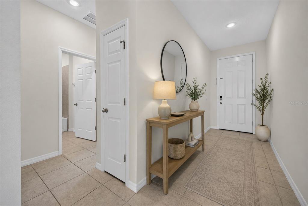 A bright entryway features tile flooring, a wooden console table, a mirror, and a door — 1245 TUPELO TRAIL, HAINES CITY, FL