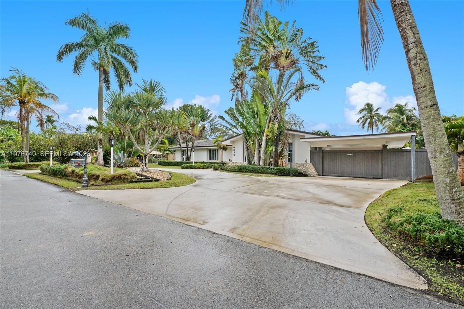 A single-story house with a large concrete driveway, a carport, and lush tropical landscaping — 9838 SW 94th Ter, Miami FL 33176, MIAMI, FL