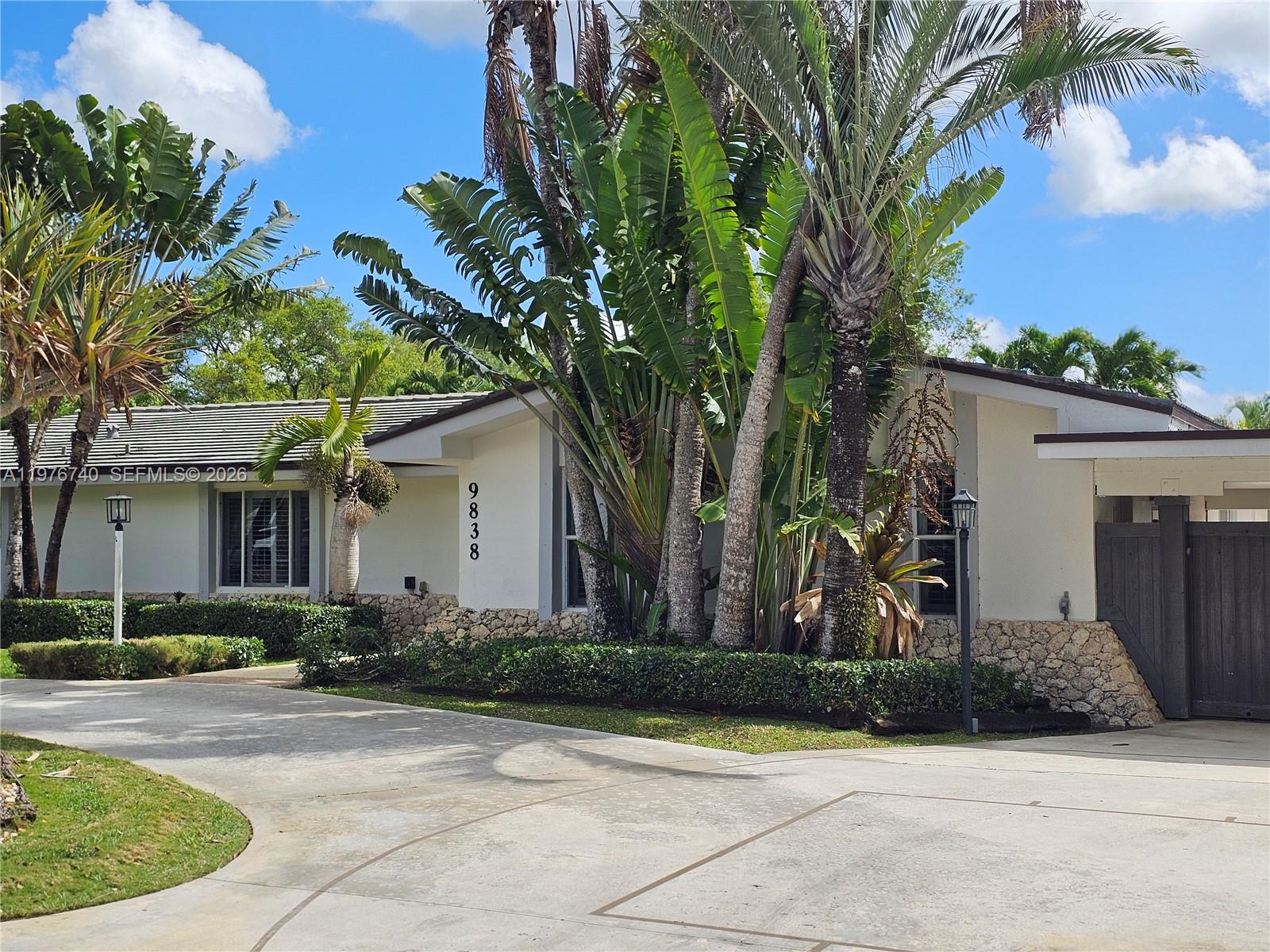 A single-story house with a stone facade, palm trees, and a concrete driveway — 9838 SW 94th Ter, Miami FL 33176, MIAMI, FL