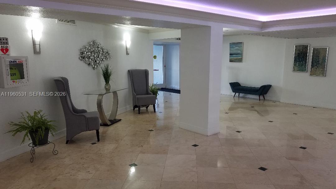 A bright lobby features tile floors, gray armchairs, a console table, and wall art — 800 Parkview Dr # 416, Hallandale Beach FL 33009, HALLANDALE BEACH, FL
