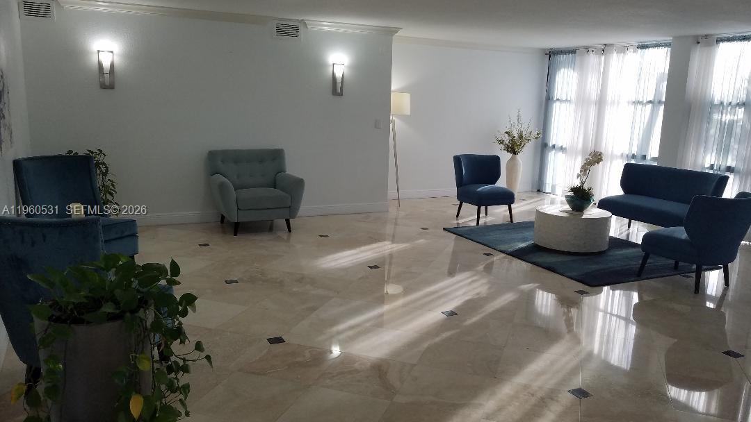 A spacious, light-filled lobby features marble floors, blue seating, and floor-to-ceiling windows with curtains — 800 Parkview Dr # 416, Hallandale Beach FL 33009, HALLANDALE BEACH, FL