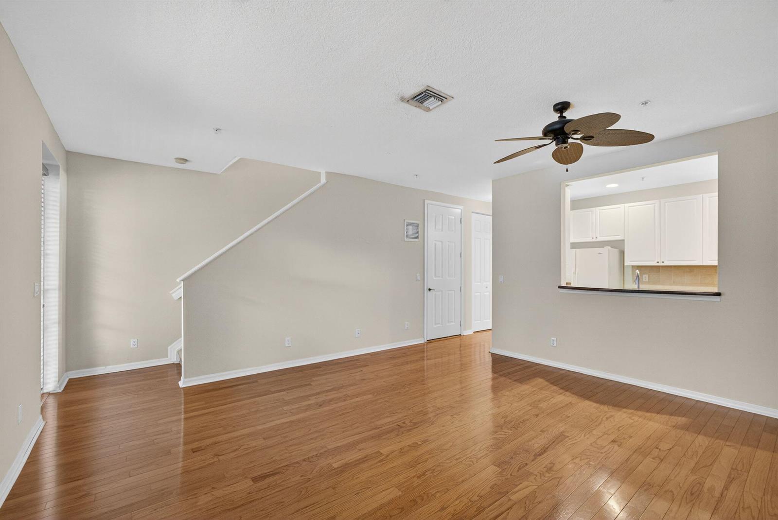 An empty room with hardwood floors, a ceiling fan, and a pass-through to the kitchen — 1562 Grande Cull Way, Jupiter FL 33458, JUPITER, FL