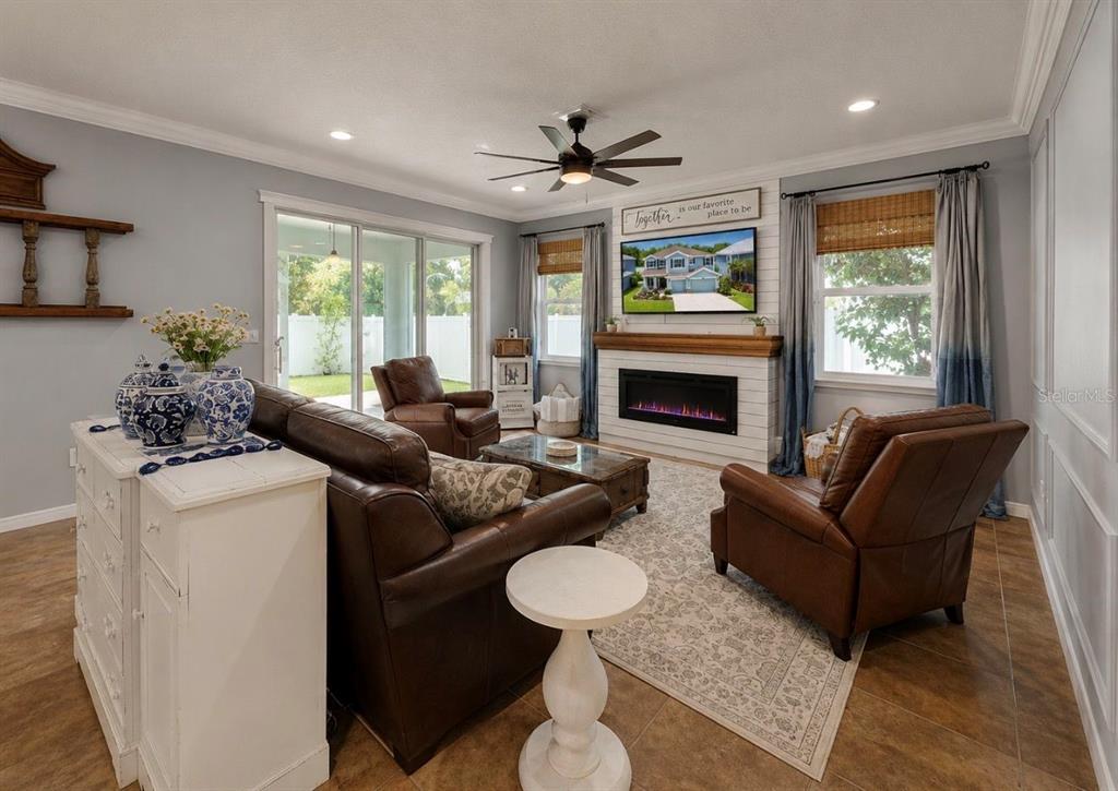 A living room features a fireplace, leather furniture, a ceiling fan, and sliding glass doors — 12426 FAIRLAWN DRIVE, RIVERVIEW, FL