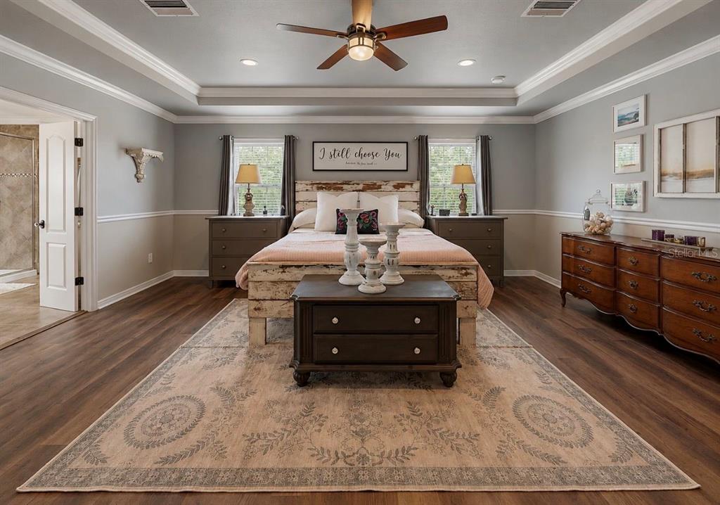 A bedroom features a rustic bed, a patterned area rug, and a wooden dresser — 12426 FAIRLAWN DRIVE, RIVERVIEW, FL