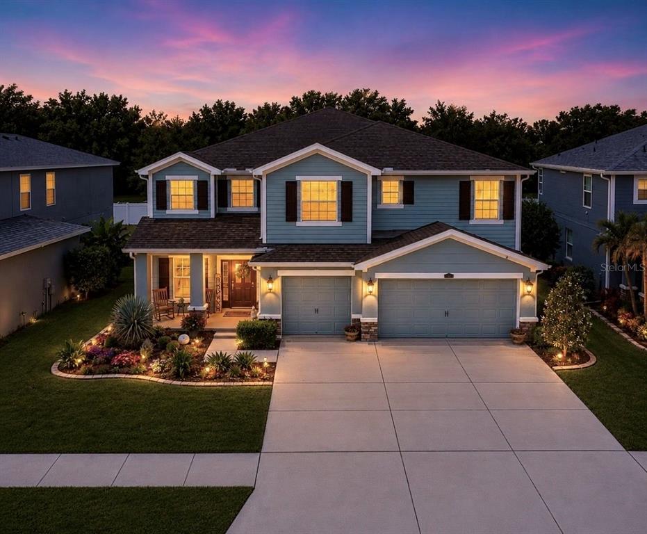 A two-story blue house with a three-car garage and a landscaped front yard at sunset — 12426 FAIRLAWN DRIVE, RIVERVIEW, FL