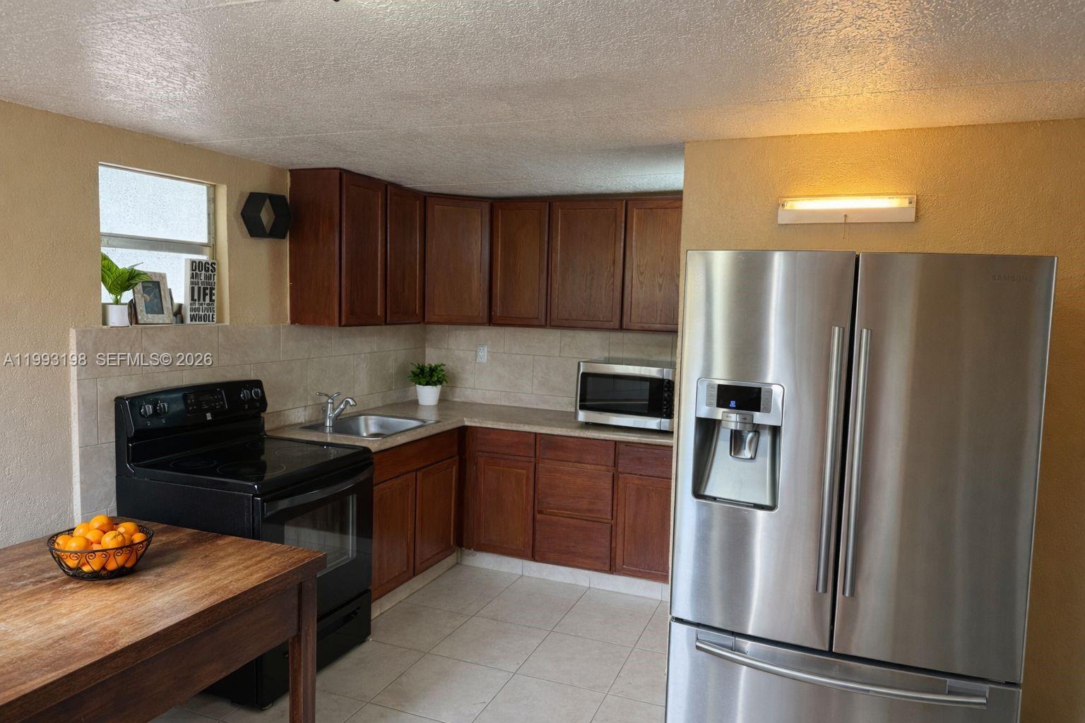 A kitchen features dark wood cabinets, stainless steel appliances, and a light-colored tiled floor — 2353 SW 2nd St, Miami FL 33135, MIAMI, FL
