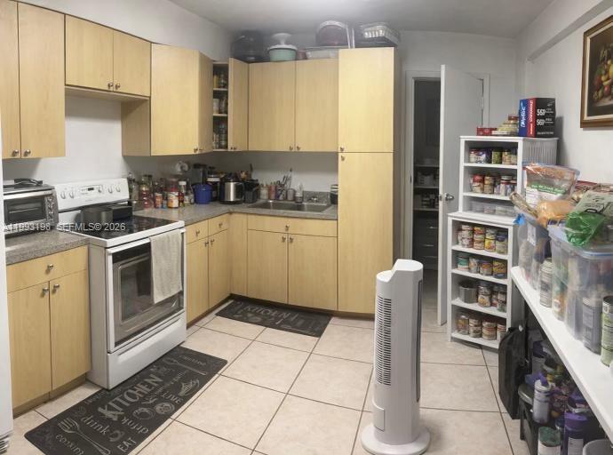 A kitchen features light wood cabinets, a white stove, and a white storage shelving unit — 2353 SW 2nd St, Miami FL 33135, MIAMI, FL