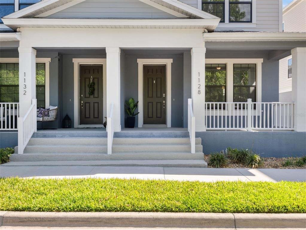 The exterior of a two-story duplex features a shared front porch with two entry doors — 1128 SPOTTED SANDPIPER LOOP, WINTER SPRINGS, FL