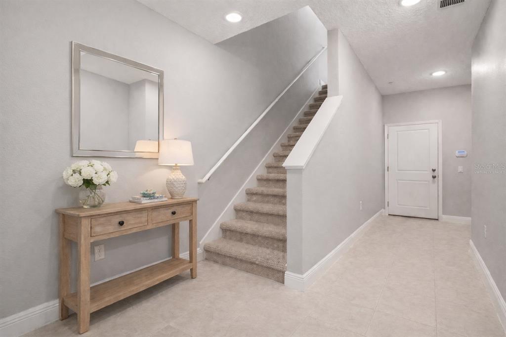 A foyer features a wooden console table, a mirror, and stairs leading to an upper level — 1128 SPOTTED SANDPIPER LOOP, WINTER SPRINGS, FL