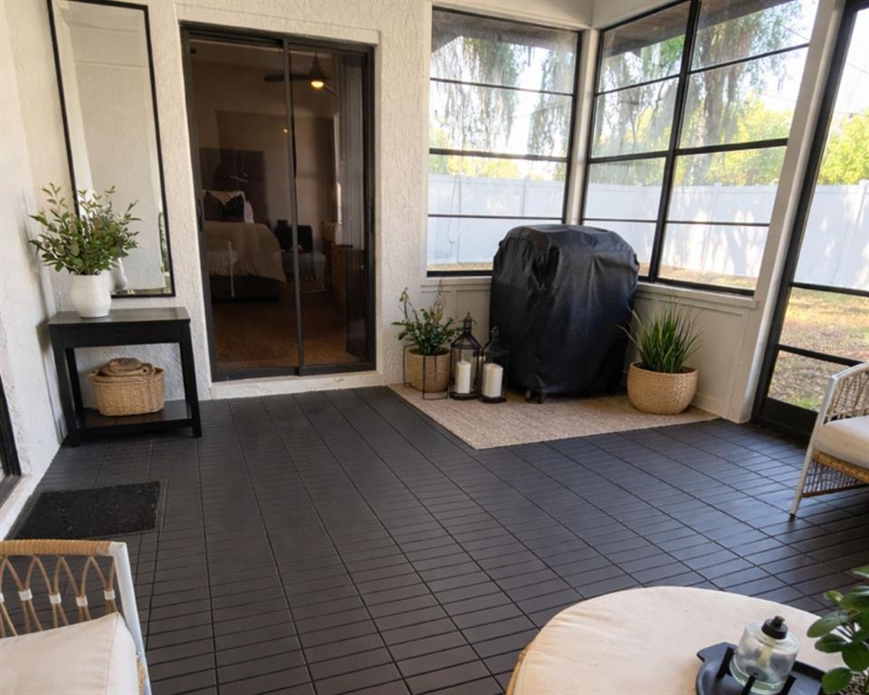 A screened-in porch features dark tiled flooring, a grill, and sliding glass doors to a bedroom — 1413 SANDALWOOD DRIVE, PLANT CITY, FL
