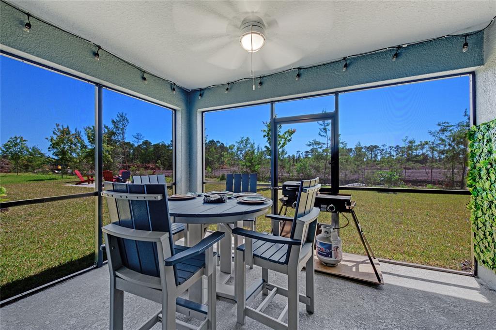 A screened-in patio features a dining set, a grill, and a ceiling fan — 1362 CORK DRIVE, ORMOND BEACH, FL