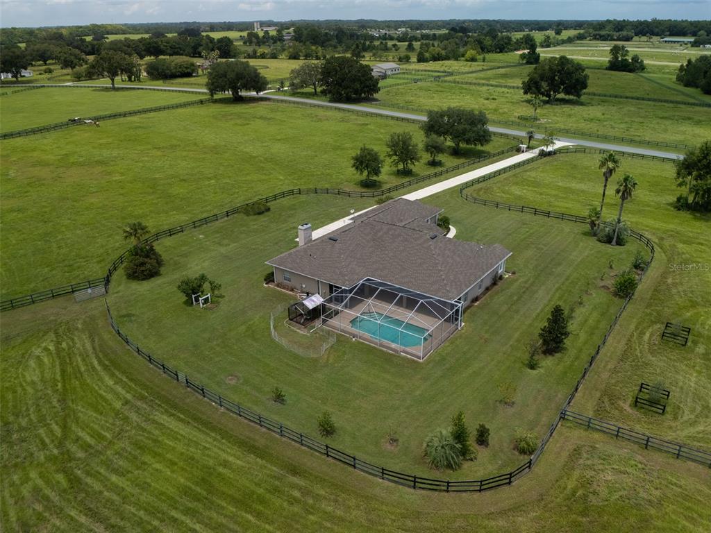 An aerial view shows a house with a screened-in pool on a large fenced property — 1500 NW 114TH LOOP, OCALA, FL
