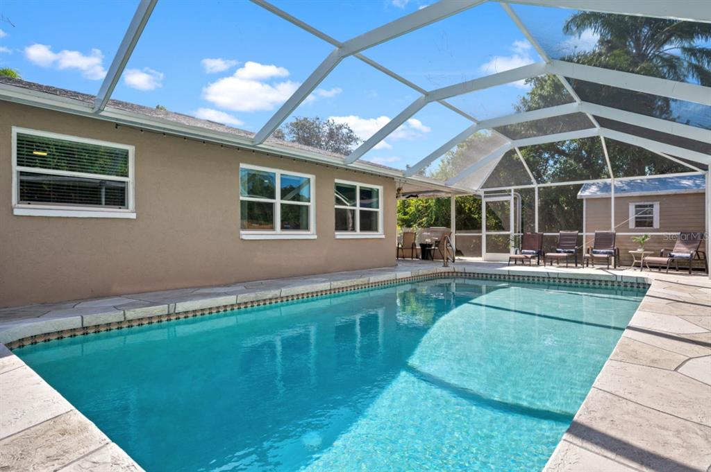 A swimming pool with a stone deck is enclosed by a screened lanai — 874 ACADIA ROAD, VENICE, FL
