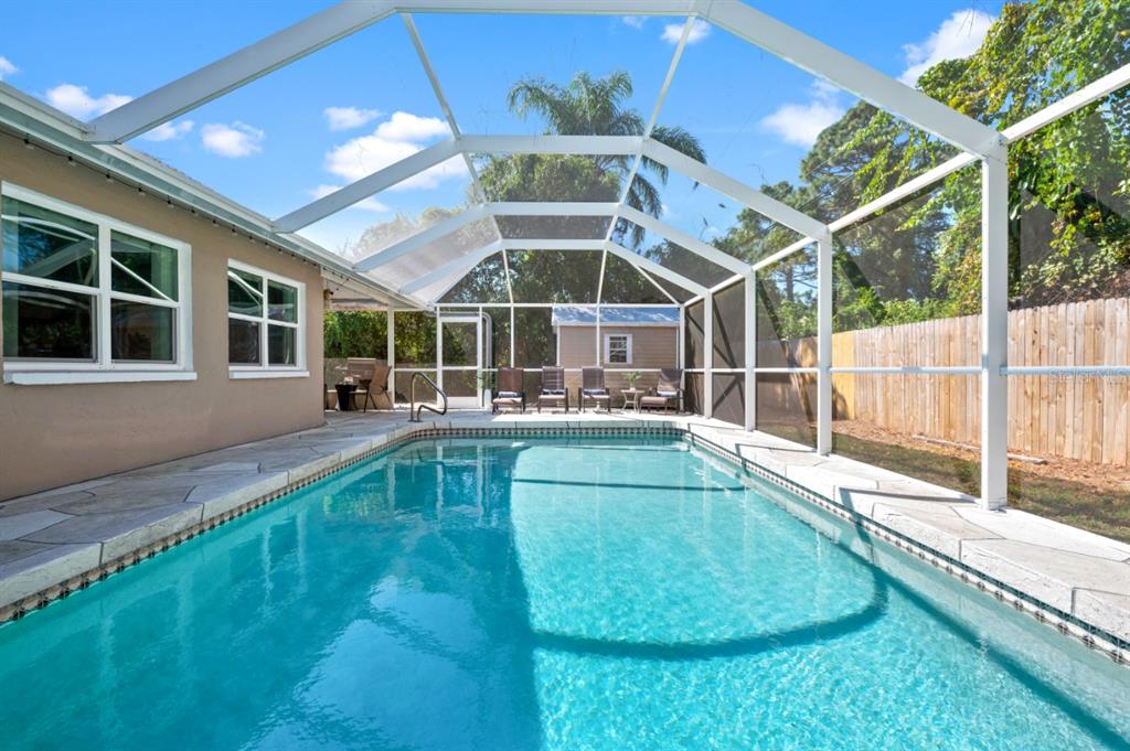 A swimming pool with a screened-in enclosure and a patio area in a backyard — 874 ACADIA ROAD, VENICE, FL