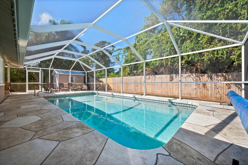 A rectangular swimming pool is enclosed by a screened lanai with a stone-patterned patio — 874 ACADIA ROAD, VENICE, FL