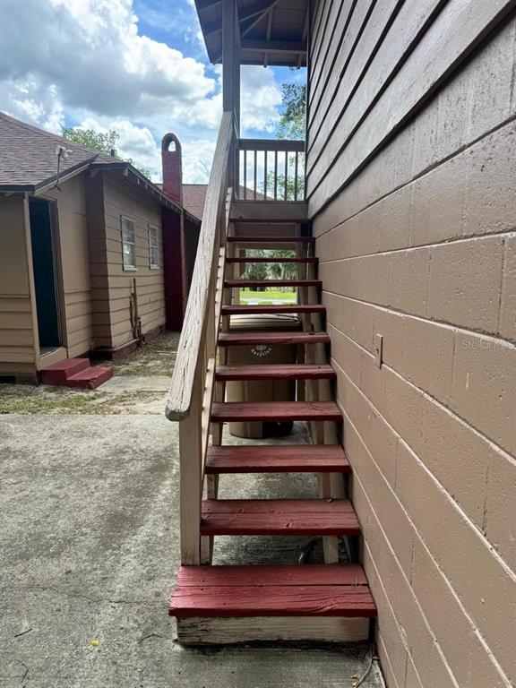 An exterior view of a wooden staircase leading to a second-story landing — 311 NE SANCHEZ AVENUE, OCALA, FL
