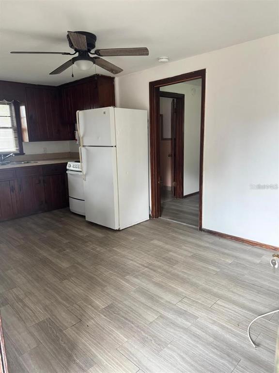 A kitchen with wood cabinets, a white refrigerator, and light-colored wood-look flooring — 311 NE SANCHEZ AVENUE, OCALA, FL