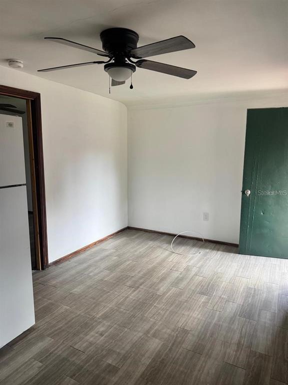 An empty room features white walls, wood-look tile flooring, and a ceiling fan — 311 NE SANCHEZ AVENUE, OCALA, FL