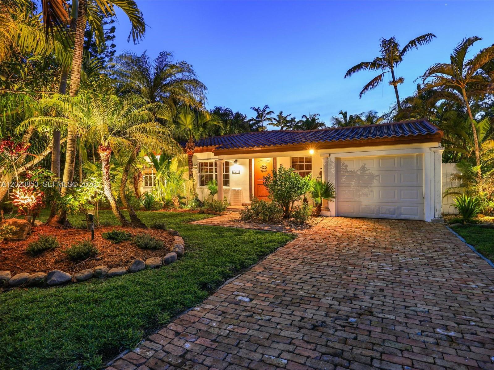 A single-story house with a brick driveway, tiled roof, and lush tropical landscaping at dusk — 5644 SW 69th Ave, Miami FL 33143, MIAMI, FL