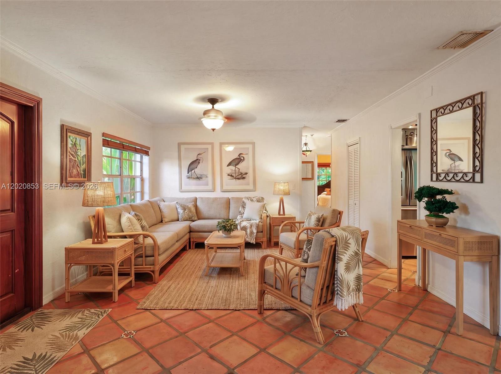 A living room features rattan furniture, a sectional sofa, terracotta tile floors, and wall art — 5644 SW 69th Ave, Miami FL 33143, MIAMI, FL