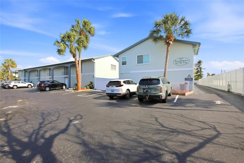 An exterior view of a light green townhouse complex with a parking lot and palm trees — 10125 MANATEE AVENUE W UNIT A4, BRADENTON, FL