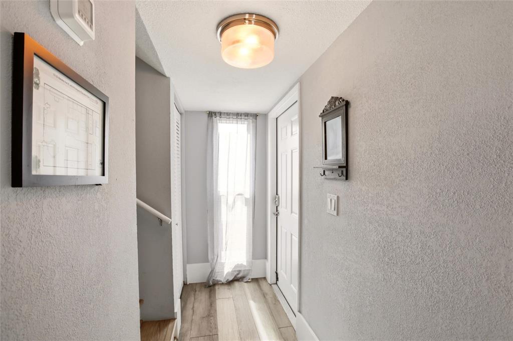 A bright entryway features light wood-look flooring, a white door, and a flush-mount ceiling light — 10125 MANATEE AVENUE W UNIT A4, BRADENTON, FL