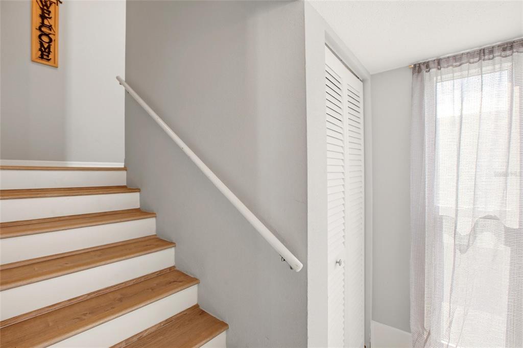 A staircase with wood treads and white risers sits beside a white louvered closet door — 10125 MANATEE AVENUE W UNIT A4, BRADENTON, FL