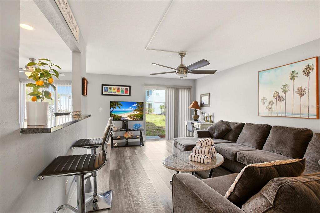 A living room features a sectional sofa, a breakfast bar, and a sliding glass door — 10125 MANATEE AVENUE W UNIT A4, BRADENTON, FL